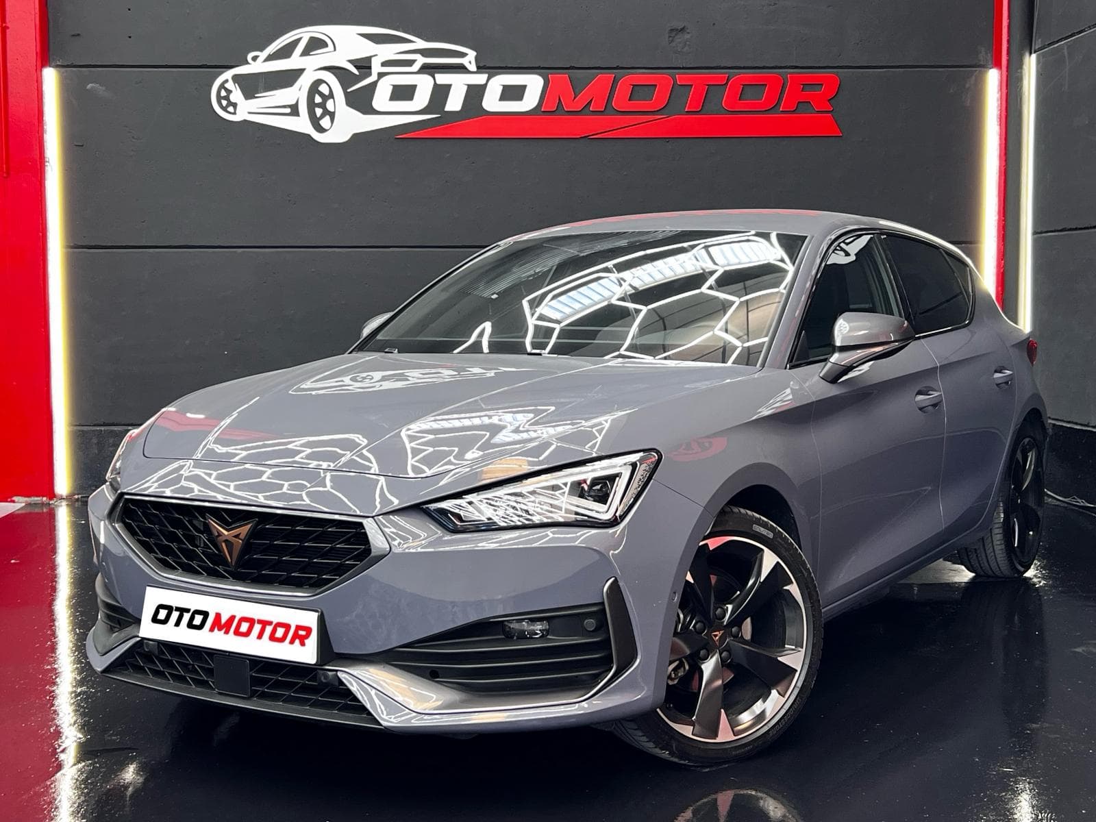 CUPRA León e-Hybrid gris, vista delantera izquierda en showroom OtoMotor