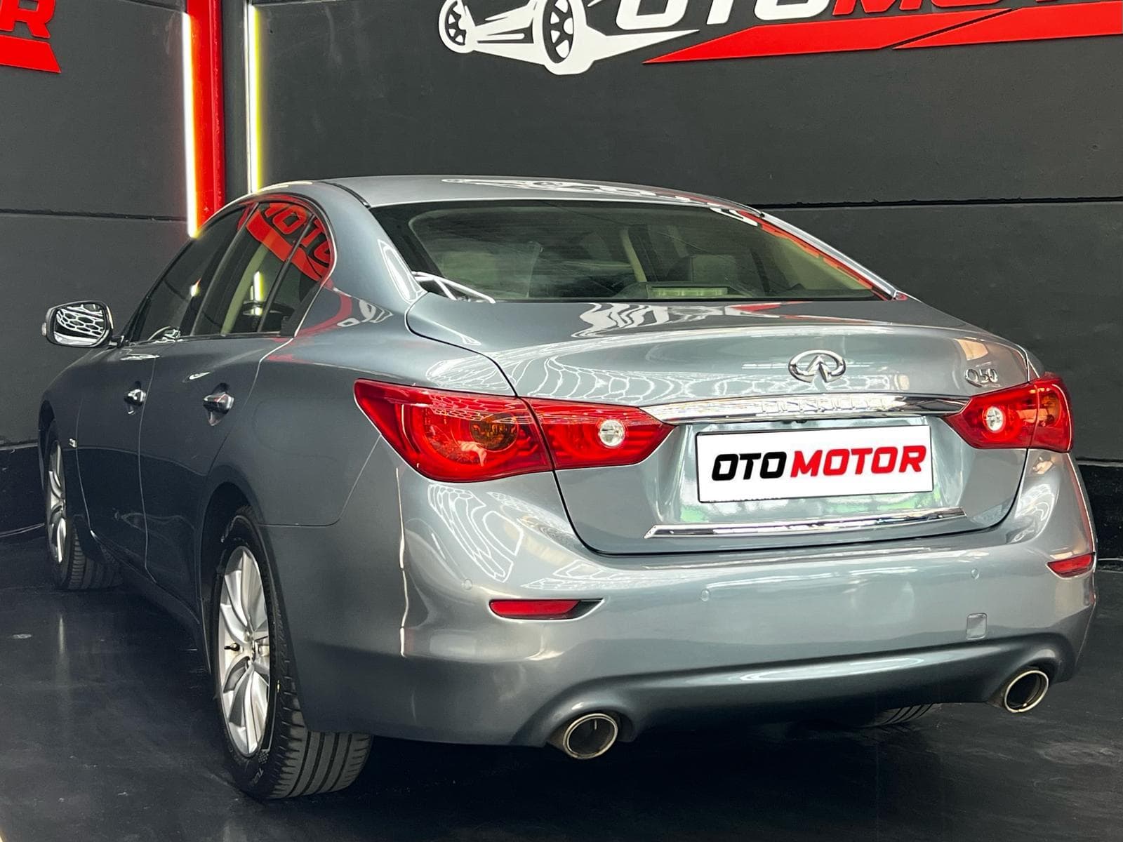 Infiniti Q50 gris 2017, vista trasera izquierda con escape deportivo