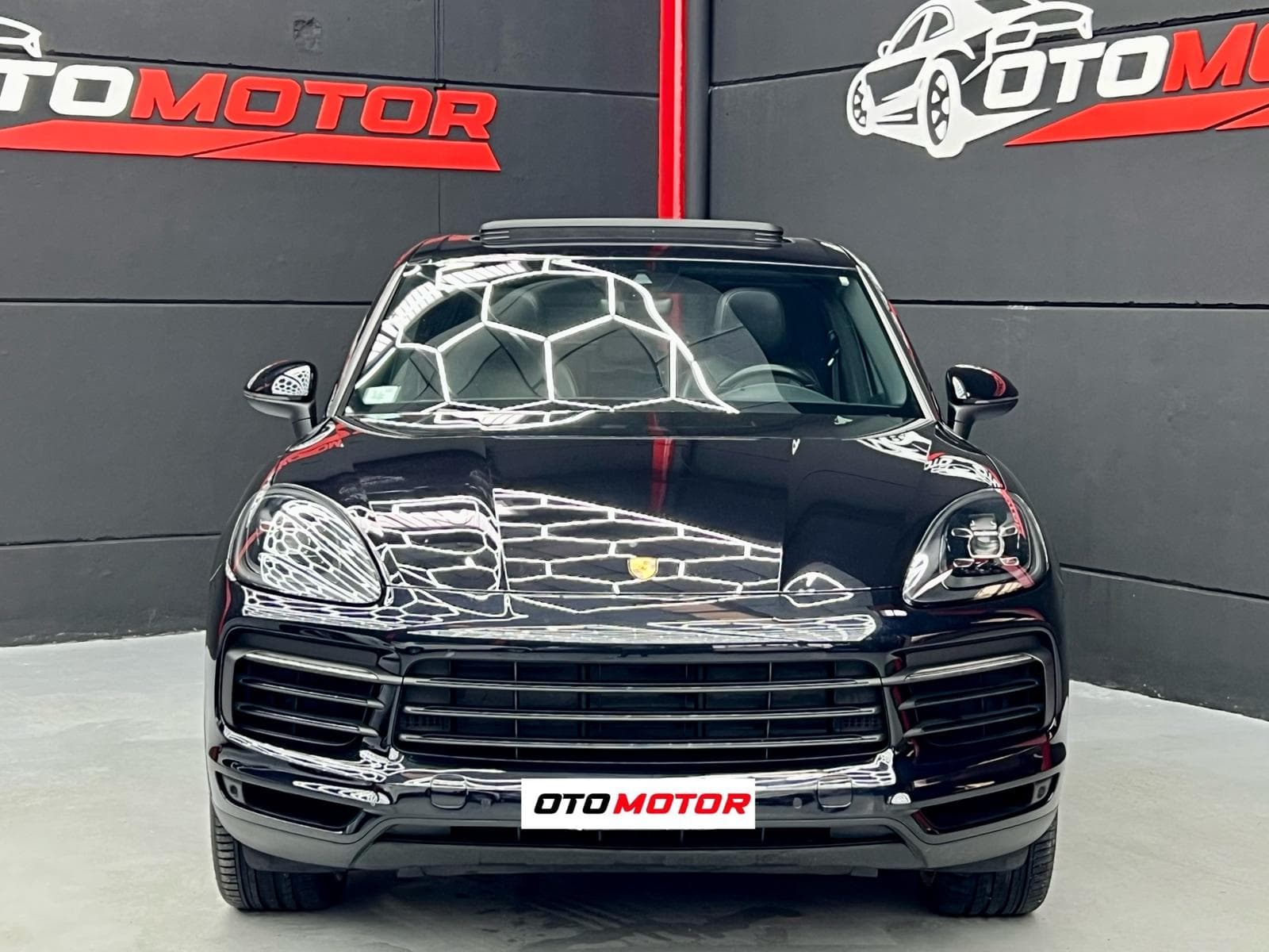 Porsche Cayenne negro 2020 con llantas doradas, vista frontal en showroom OtoMotor