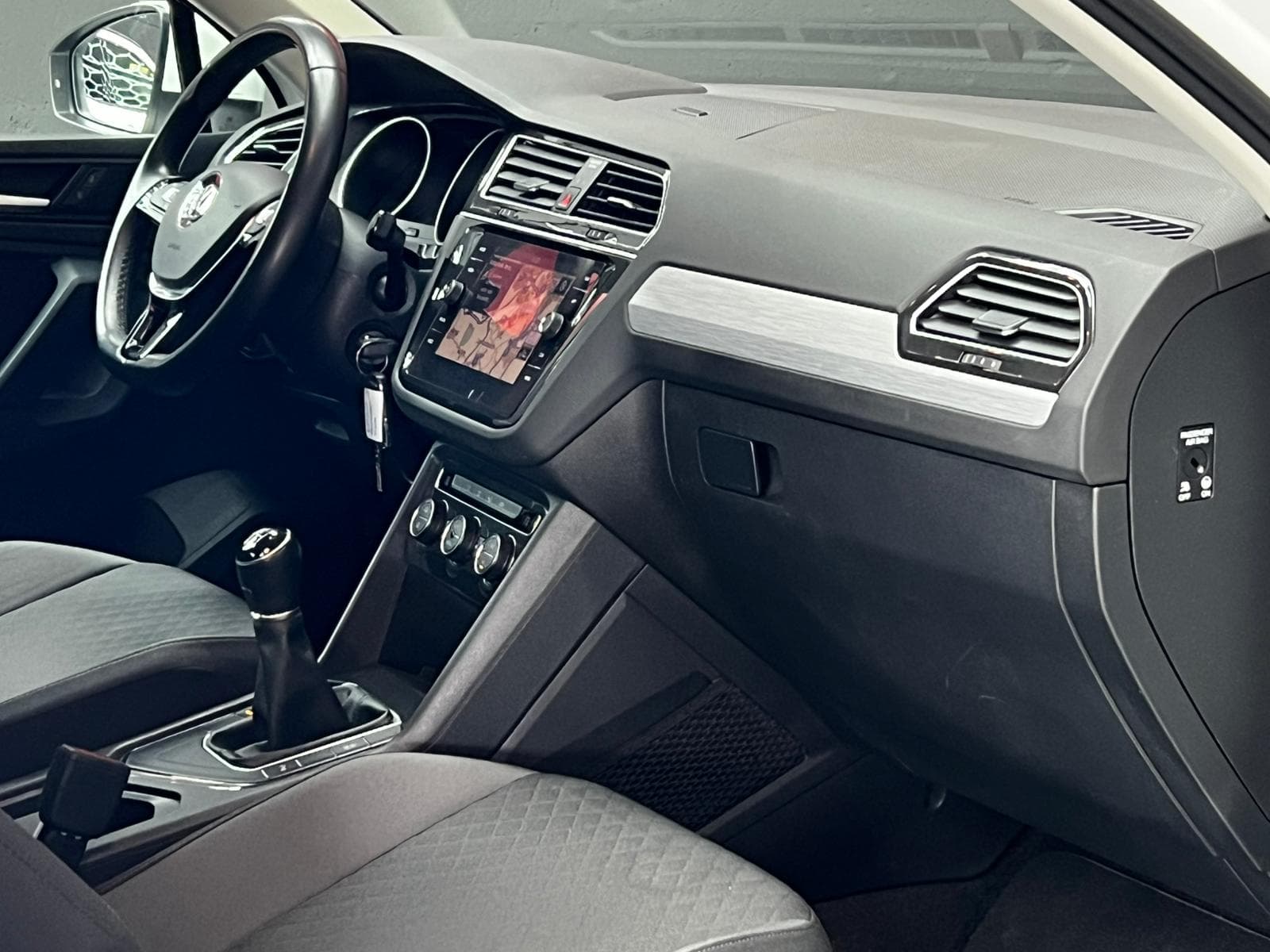 Interior Volkswagen Tiguan blanco con salpicadero, pantalla de navegación y climatizador bizona